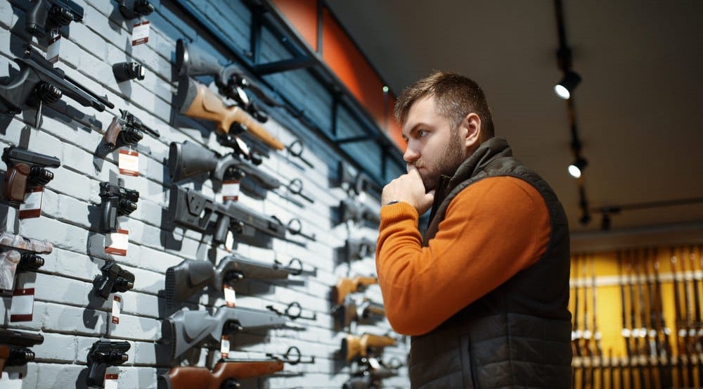 Man looking at wall of firearms